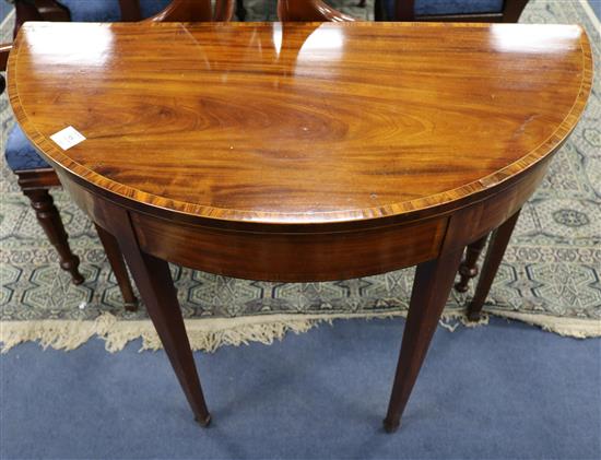 A George III mahogany demi-lune folding top card table, tulipwood-banded, W.3ft 1in.